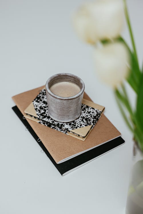 Free A Cup of Foamy Drink on a Pile of Notebooks Stock Photo