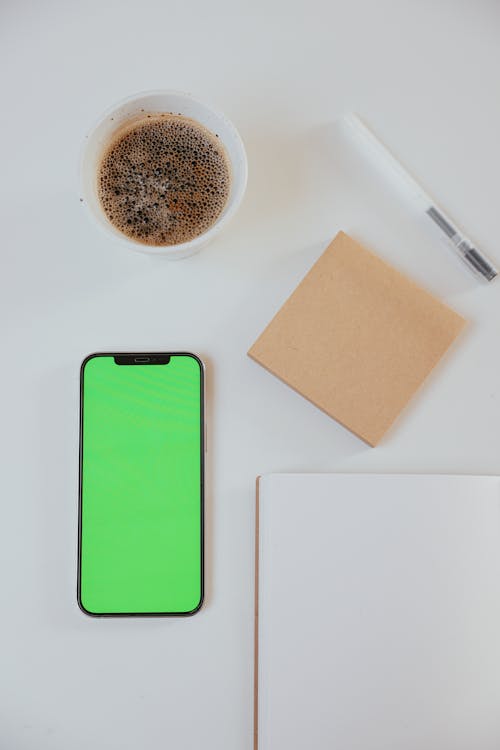 Close-Up Shot of a Smartphone beside a Cup of Coffee