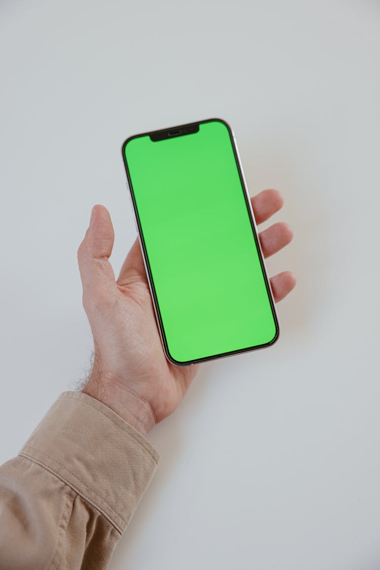 A Person Holding A Phone With A Green Screen