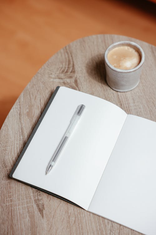 Silver Pen on Notebook Beside a Cup of Coffee