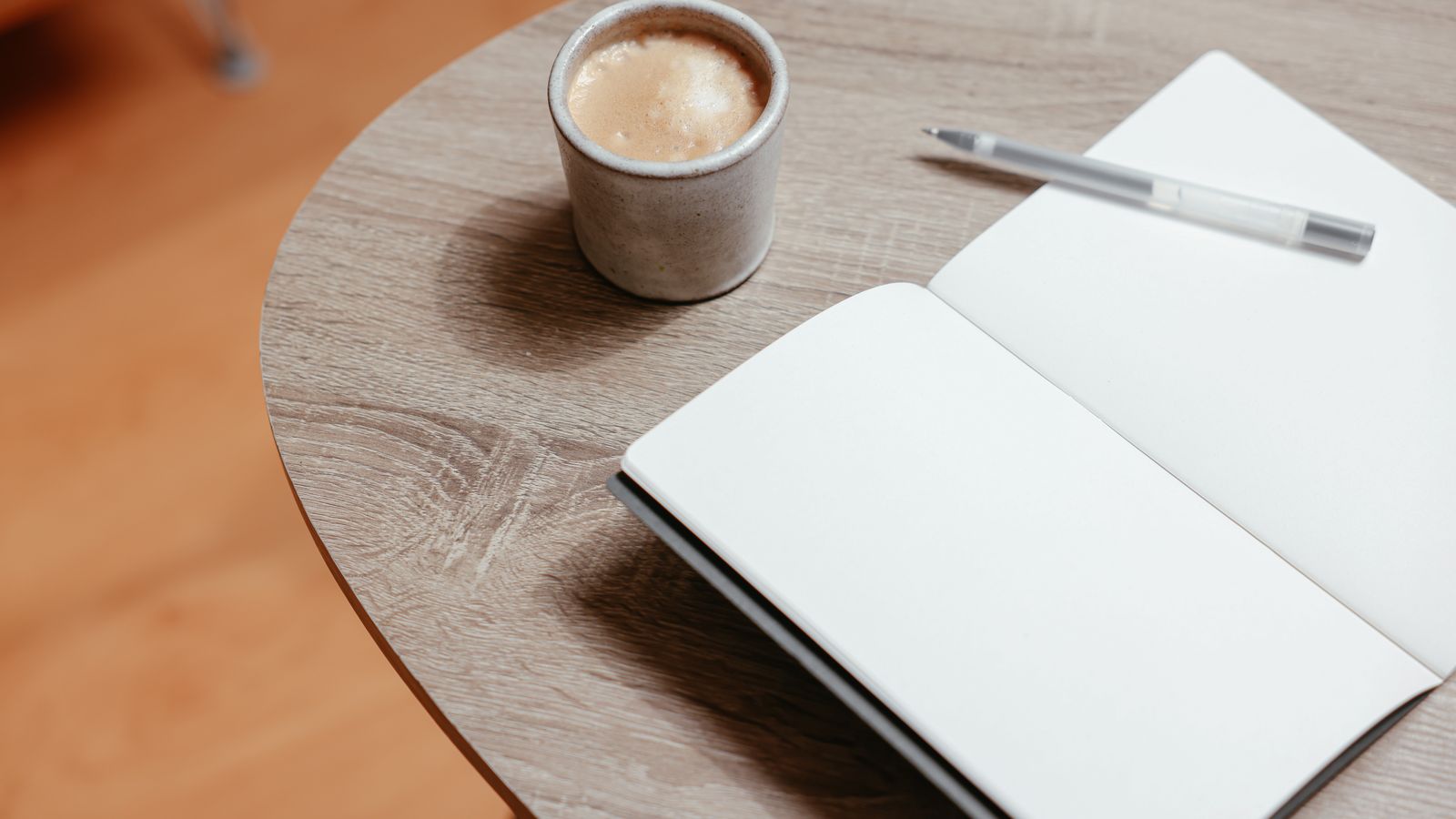 Caderno e chávena de café numa mesa.