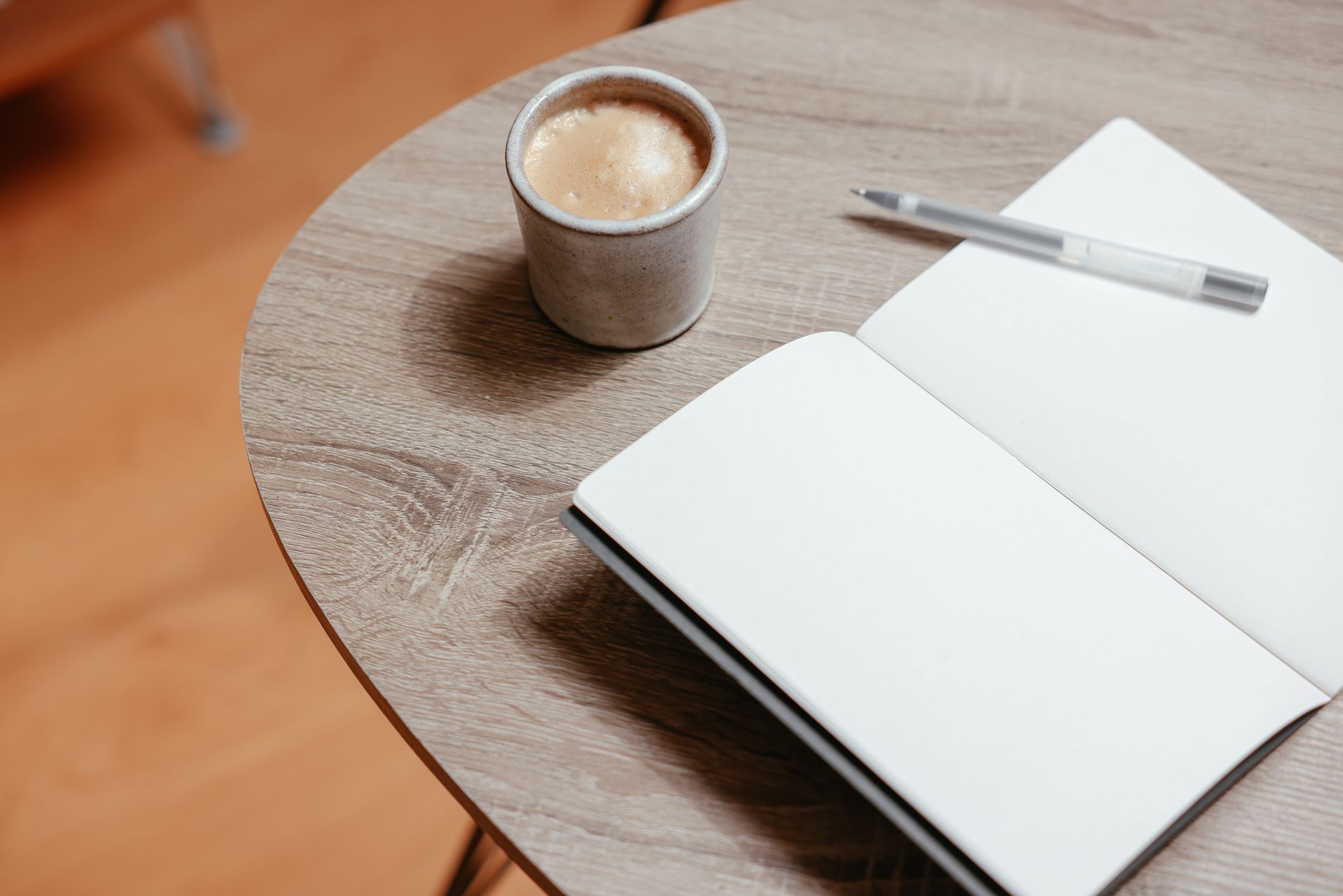 Open notebook with blank pages and coffee on a wooden table, ideal for creativity.