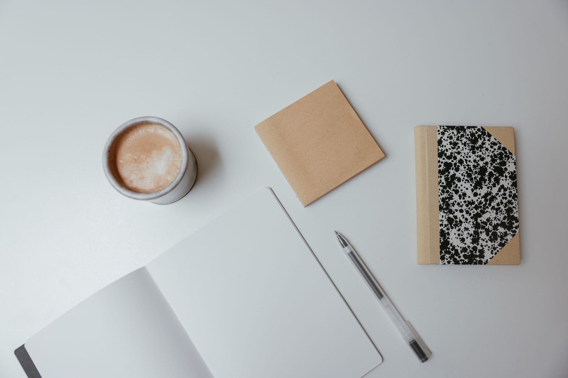 Overhead view of a warm desk with a notebook, blank cards and a pen in neutral tones