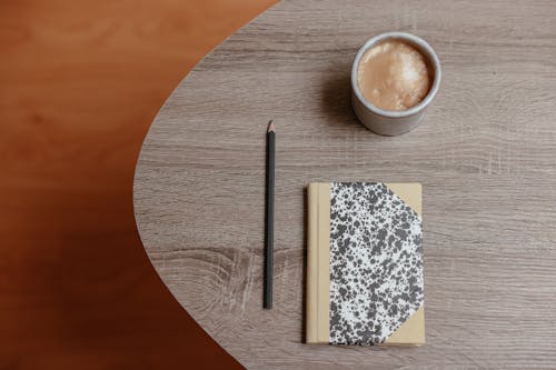 Free Cup of Coffee, Pencil and Notepad on Brown Wooden Table Stock Photo