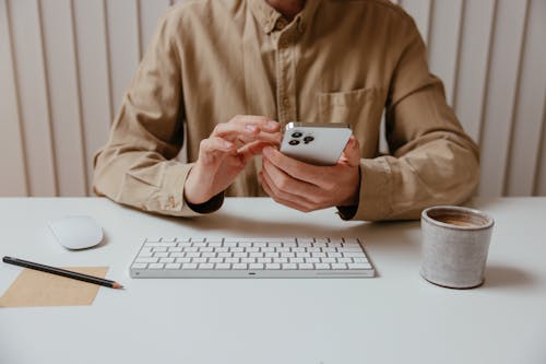 Person in Brown Dress Up Shirt Using Smartphone