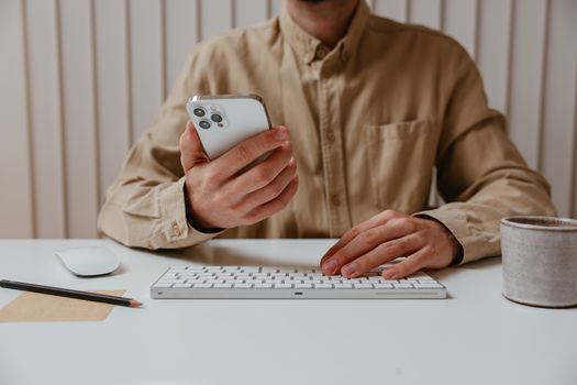 Casual office setting where a man uses a smartphone and keyboard, illustrating modern work practices.