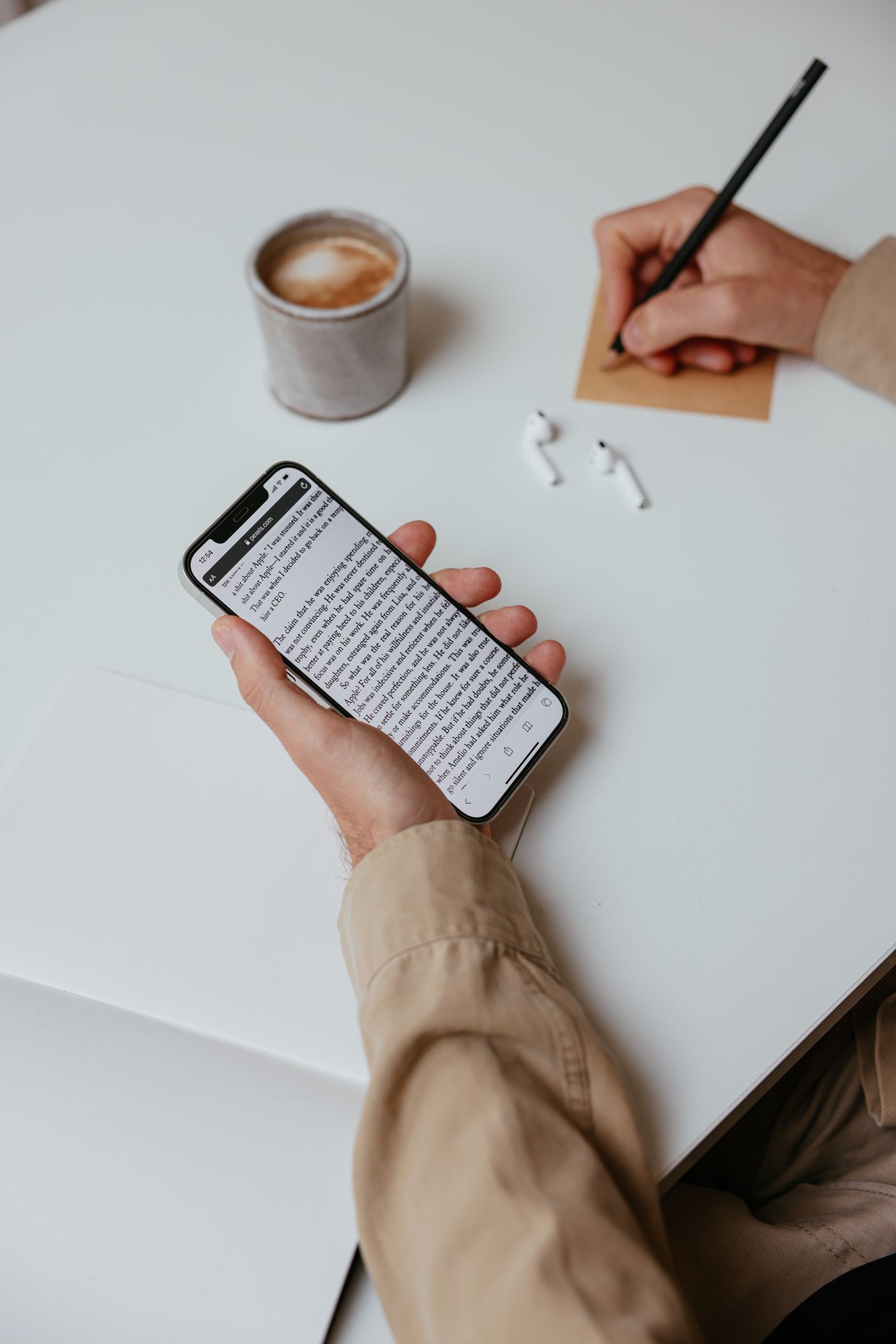 Person holding a smartphone beside a notebook at a desk