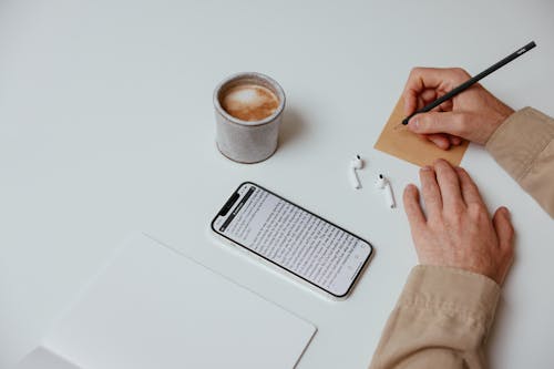 Person Writing a Note on White Table