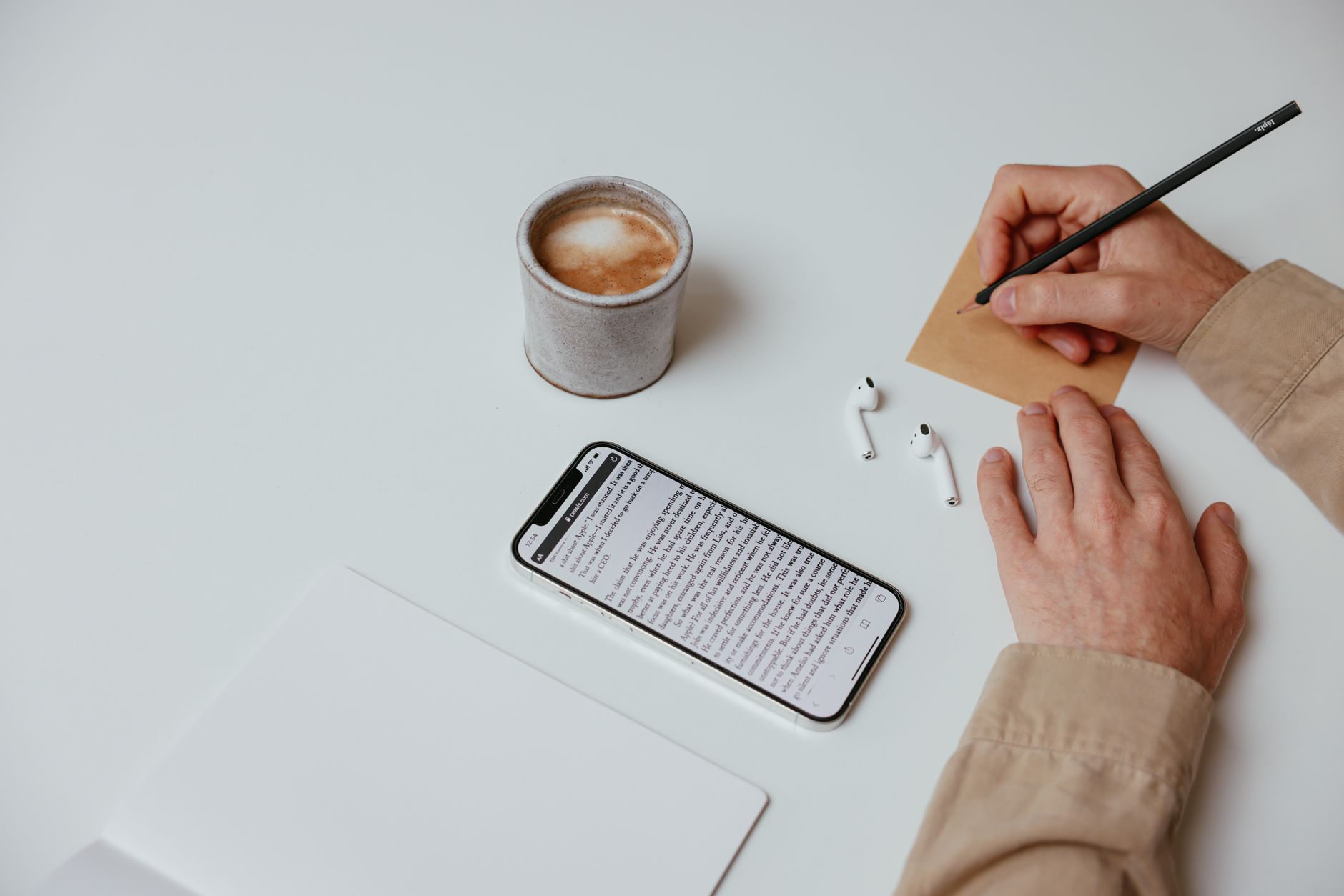 Top view of a minimalist workspace with a coffee cup, smartphone, and writing notepad.