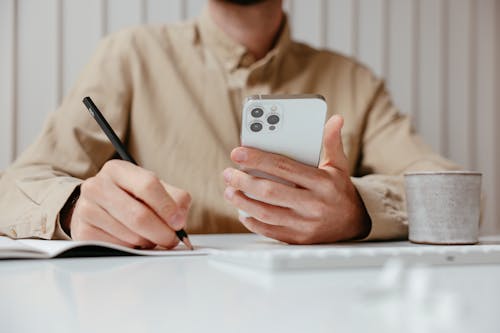 Free Person in Beige Button Up Shirt Holding White Mobile Phone Stock Photo