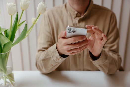 A person interacting with a smartphone at a modern and minimalistic workspace with tulips.
