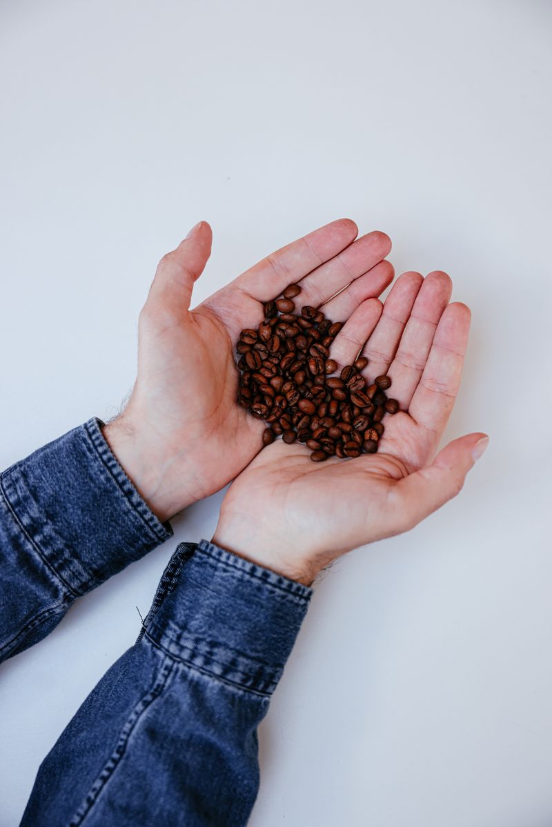 Hands holding coffee beans over an open kraft coffee bag