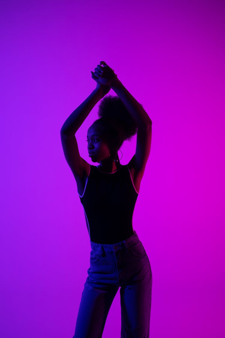 Woman With Arms Raised Above Head On Purple Background