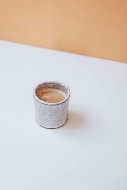 Free A minimalist ceramic coffee cup on a white table, evoking simplicity and calm. Stock Photo