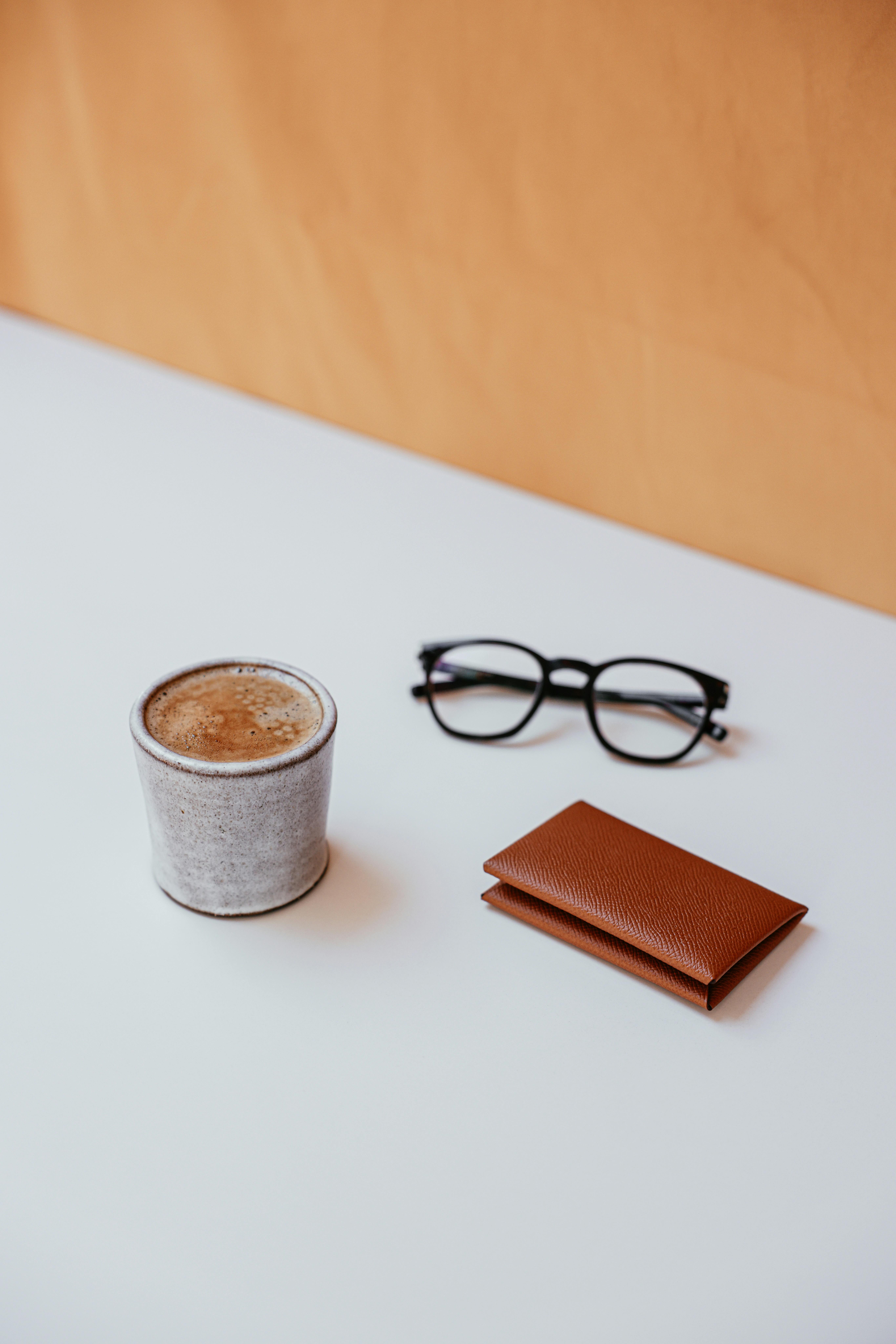 a cup of coffee wallet and eyeglasses on a table