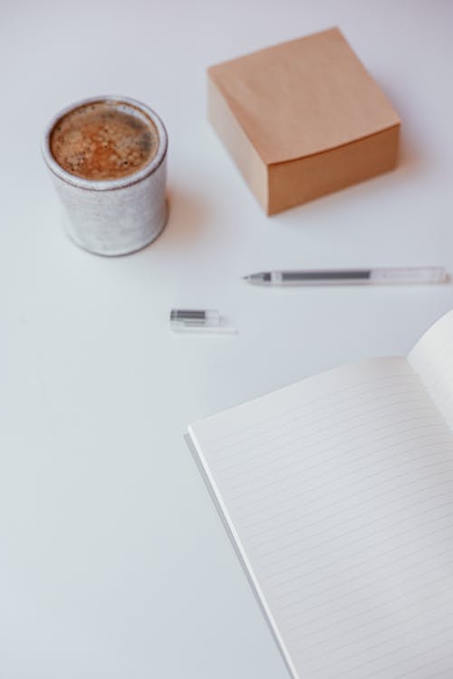 Free A Cup of Coffee, Sticky Note and Notebook on a Table Stock Photo