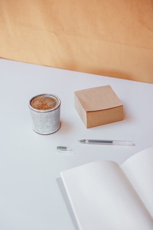 Free A Cup of Coffee, Sticky Note and Notebook on a Table Stock Photo