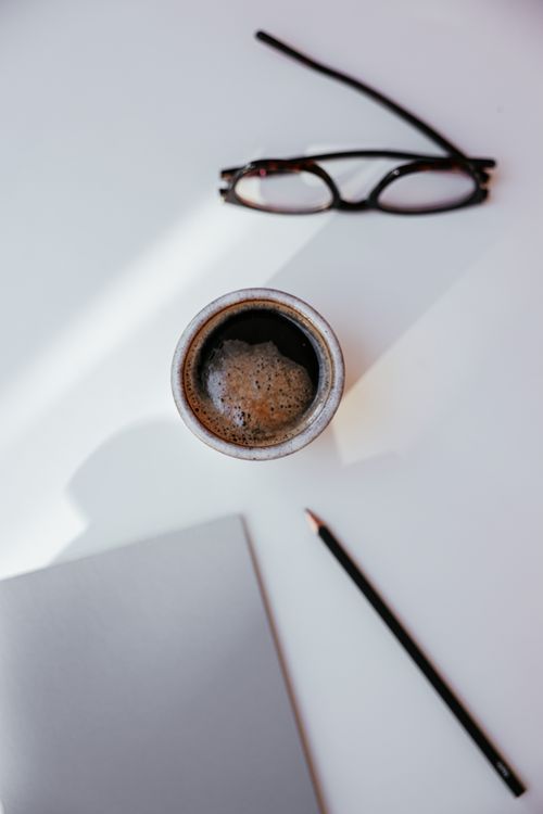 Free A top-down view of a coffee cup, glasses, and a pencil on a white background. Stock Photo