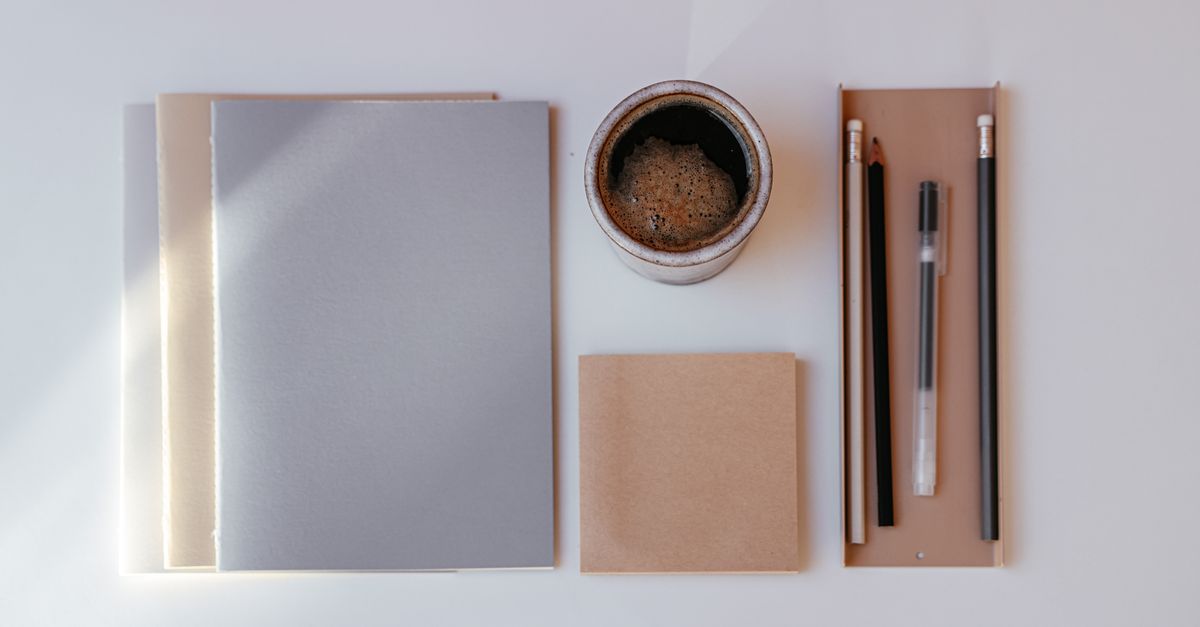 A minimalist flat lay of a notebook, a pen, and a coffee cup with the words
