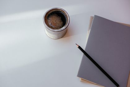 Coffee, notebook and pencil on a pale desk — photo by Cup of Couple on Pexels