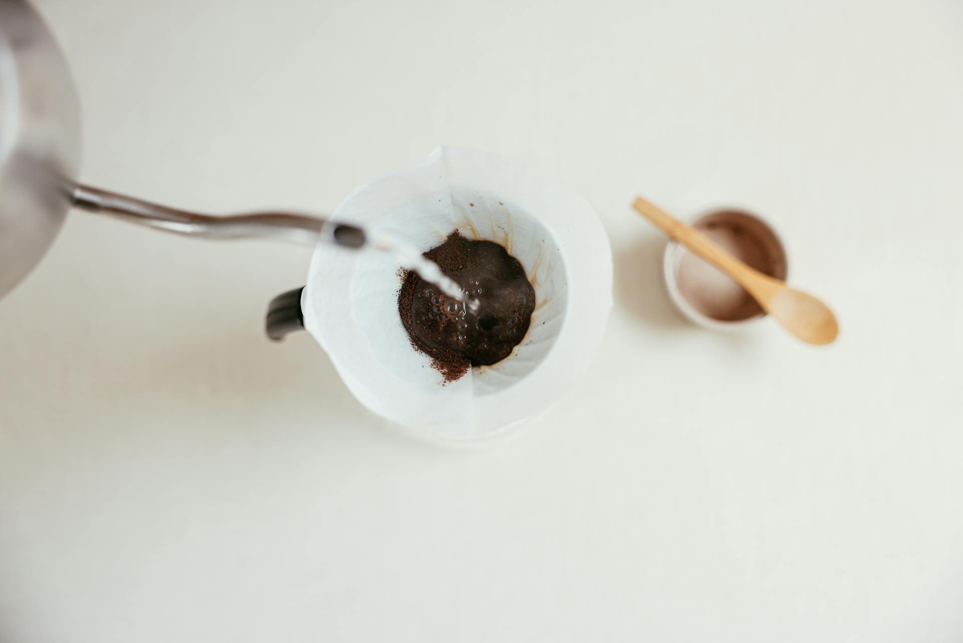 A close-up shot of pour over coffee brewing with a gooseneck kettle and filter.
