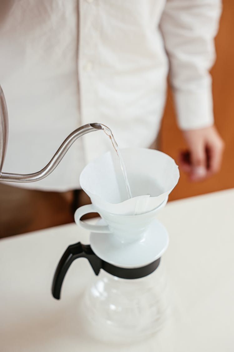 A Person Pouring Hot Water On A Pour Over Coffee Dripper