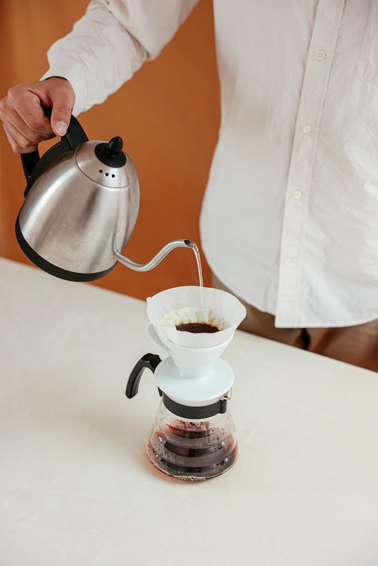 A Person Pouring Hot Water On A Pour Over Coffee Dripper