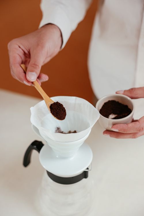 Free Detailed view of ground coffee being added to a dripper for pour over brewing. Stock Photo