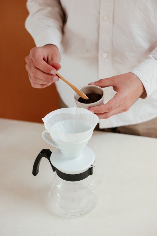 Free Hands preparing pour over coffee with a dripper and wooden spoon. Stock Photo