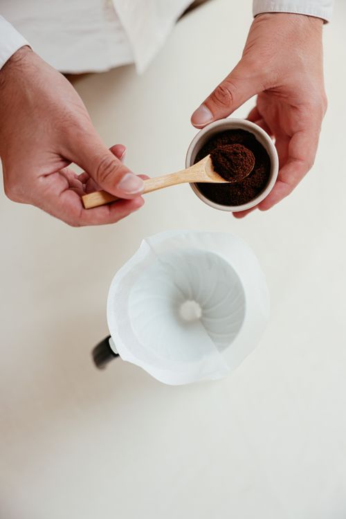 Free Hands preparing pour-over coffee with ground coffee and dripper from above. Stock Photo