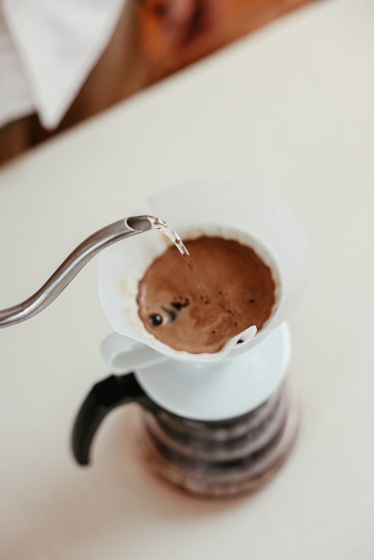 A Person Pouring Hot Water On A Pour Over Coffee Dripper