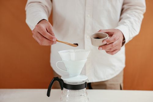 Free Close-up of a man using a dripper and filter to prepare pour over coffee. Stock Photo
