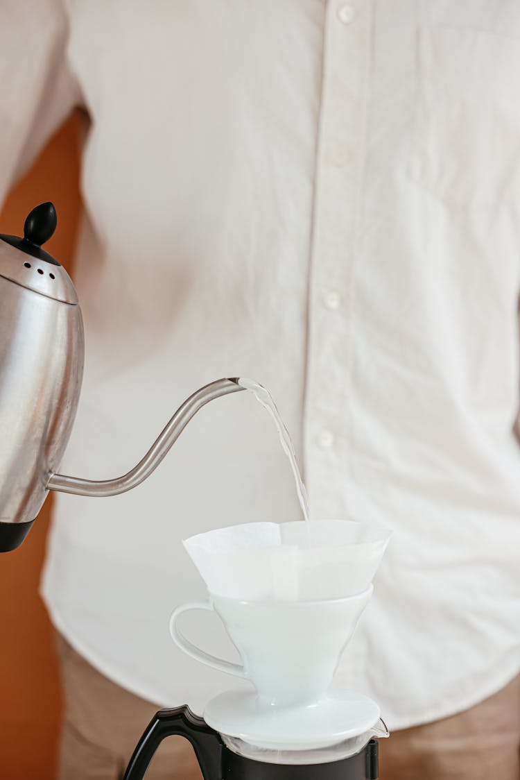 A Person Pouring Hot Water On A Pour Over Coffee Dripper