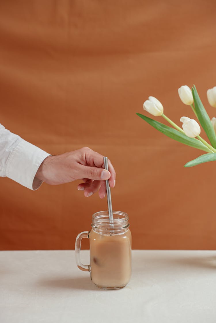 A Person Holding The Stainless Straw Of A Jar Of Drink