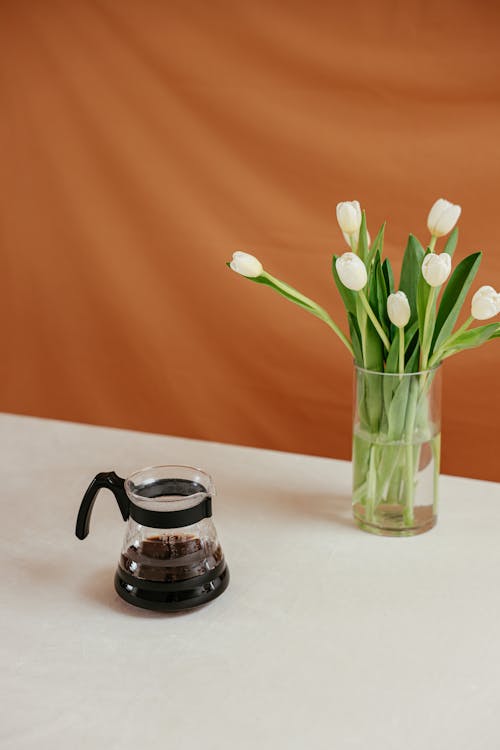 A Coffee in a Coffee Pot Beside a Vase with Flowers