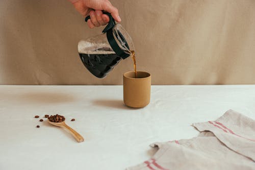 Person Pouring Coffee on Brown Ceramic Mug