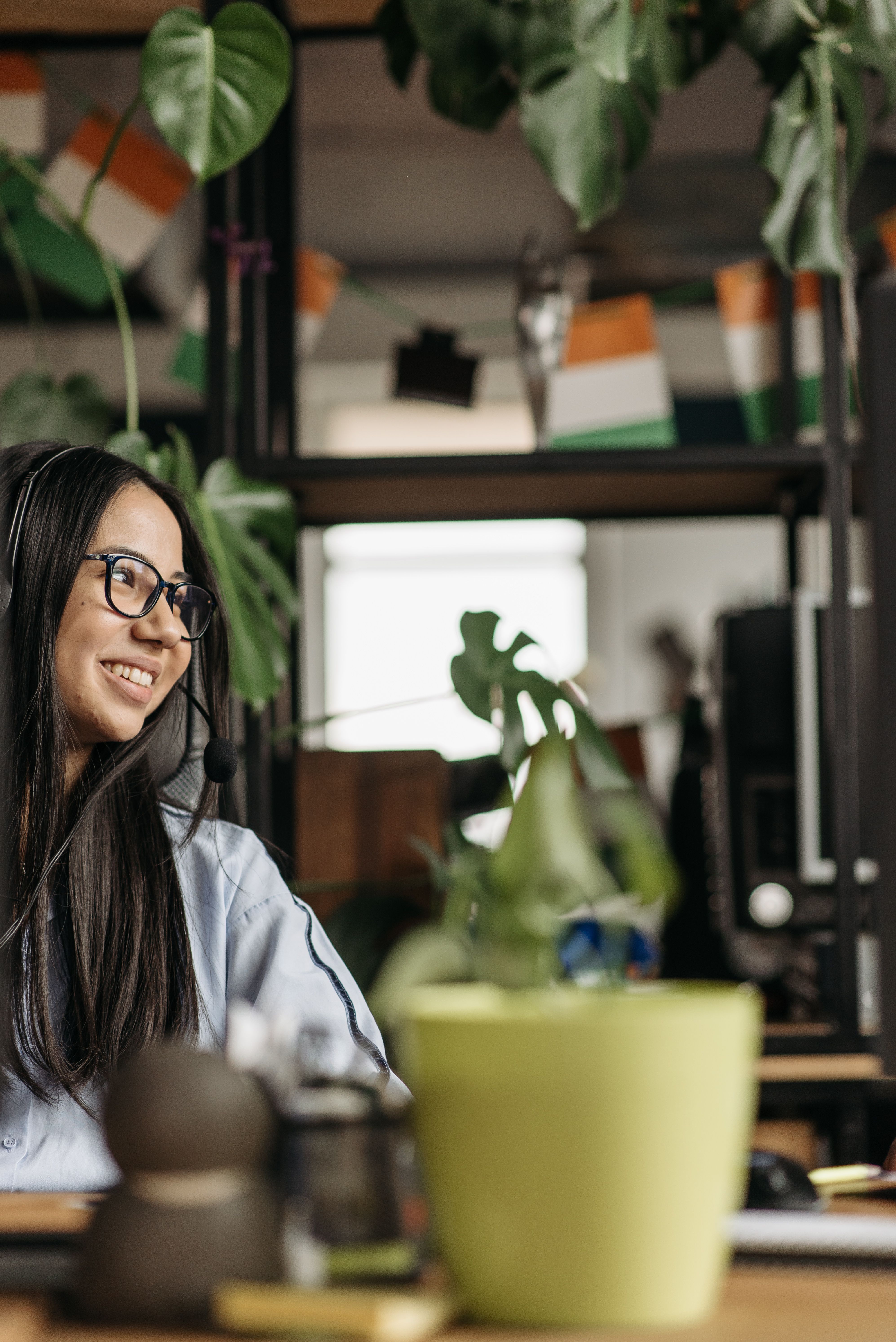 A person working at a desk with headphones on, surrounded by plants