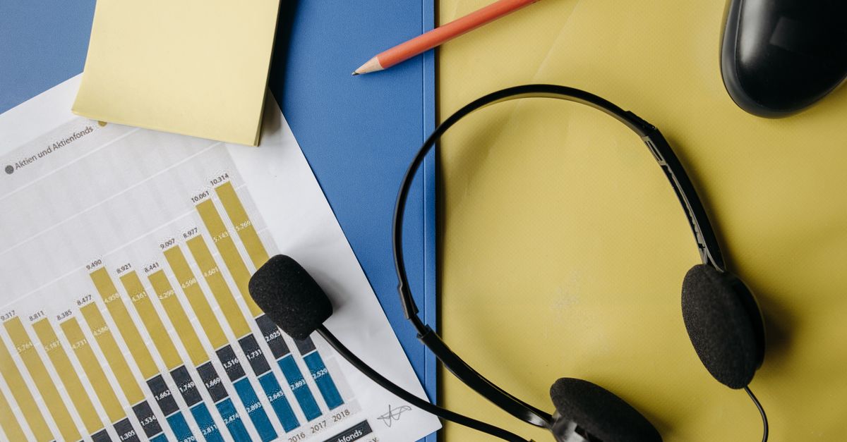 A flat lay image depicting an office desk with a headset, chart, and stationery for business use.