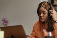 Woman in Orange Dress Shirt Using Silver Macbook