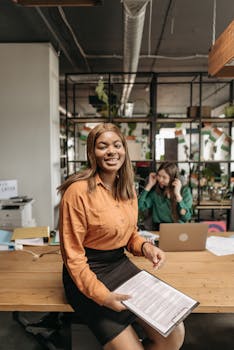 Two diverse women working in a modern office, smiling confidently.