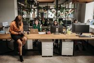 Woman in Black Dress Sitting on Brown Wooden Desk