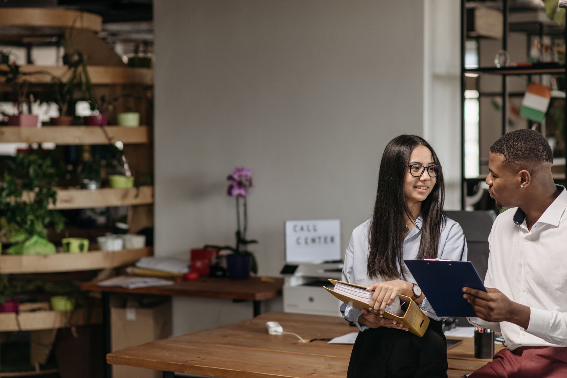 A man and woman discussing documents together in a modern office setting.