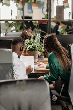 Adults collaborating at a desk with headphones in a modern office setting.