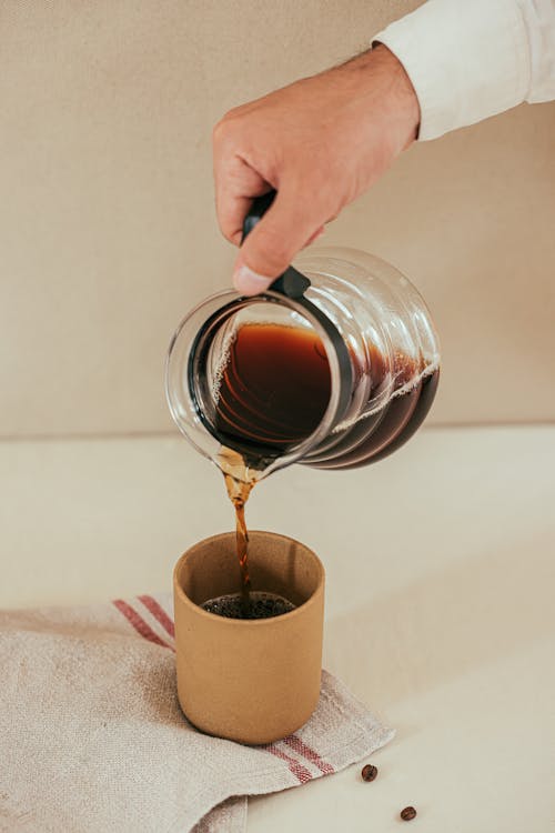 Person Pouring Coffee on brown Cup