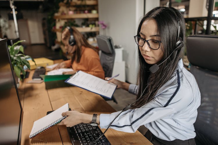 Woman Wearing Headset Holding Notebook And A Clipboard