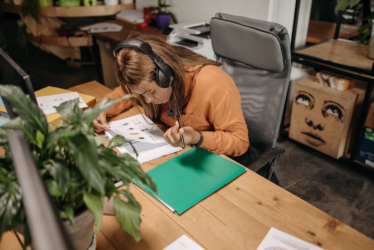 A Woman Reading A Document In Front Of Her Computer Desk