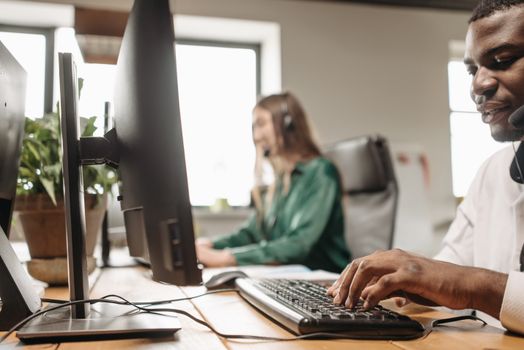 Customer support agents working at a busy call center with focus on diversity and teamwork.