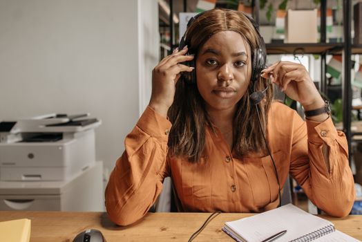 A call center agent wearing headphones, focused on work at her desk.
