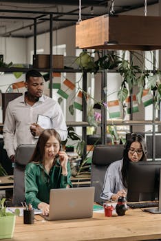 Colleagues in an office setting collaborating on tasks with technology and decor around them.