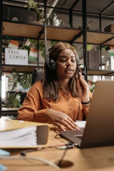 Confident African American woman working as a call center agent wearing headphones and talking on the phone.